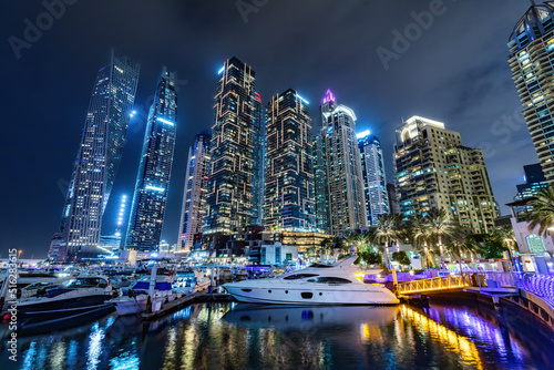 Marina with yachts and skyscrapers in Dubai UAE at night