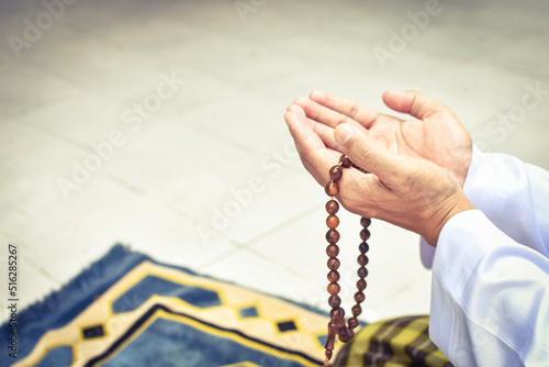 Muslim man in white session lift two hand for praying and wearing bead on hand to determine the number of prayer services.concept for Ramadan, Eid al Fitr, eid ad-ha, meditation, islamic praying