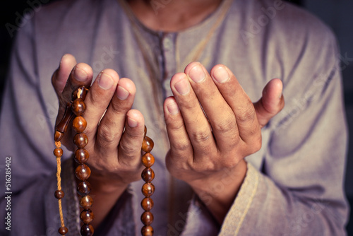 Muslim man in brown session lift two hand for praying and wearing bead on hand to determine the number of prayer services.concept for Ramadan  Eid al Fitr  eid ad-ha  meditation  islamic praying