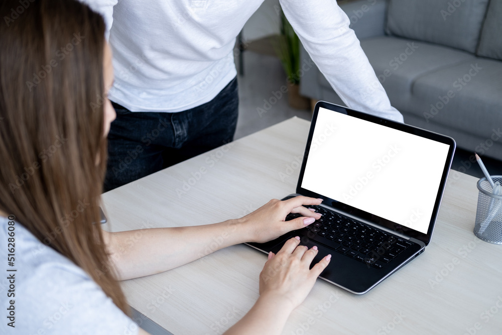 Fototapeta premium Online conference. Distance work. Computer mockup. Unrecognizable woman sitting desk typing laptop blank screen in light room interior.
