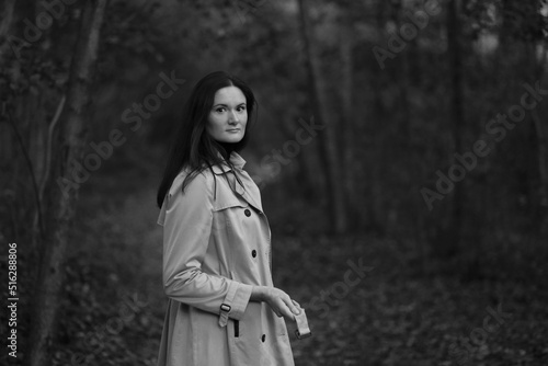 Young woman in grey coat walking in the forest in black and white © Сергей Луговский