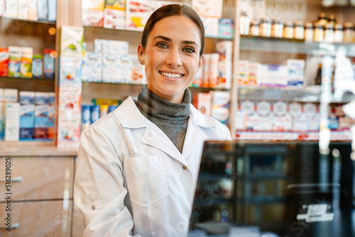 White apothecary smiling while working with till at pharmacy photo