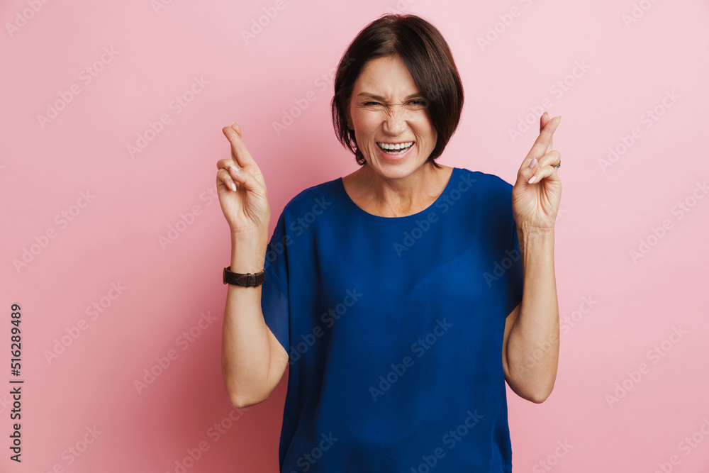 Mature brunette woman laughing while holding fingers crossed Mature brunette woman laughing while holding fingers crossed