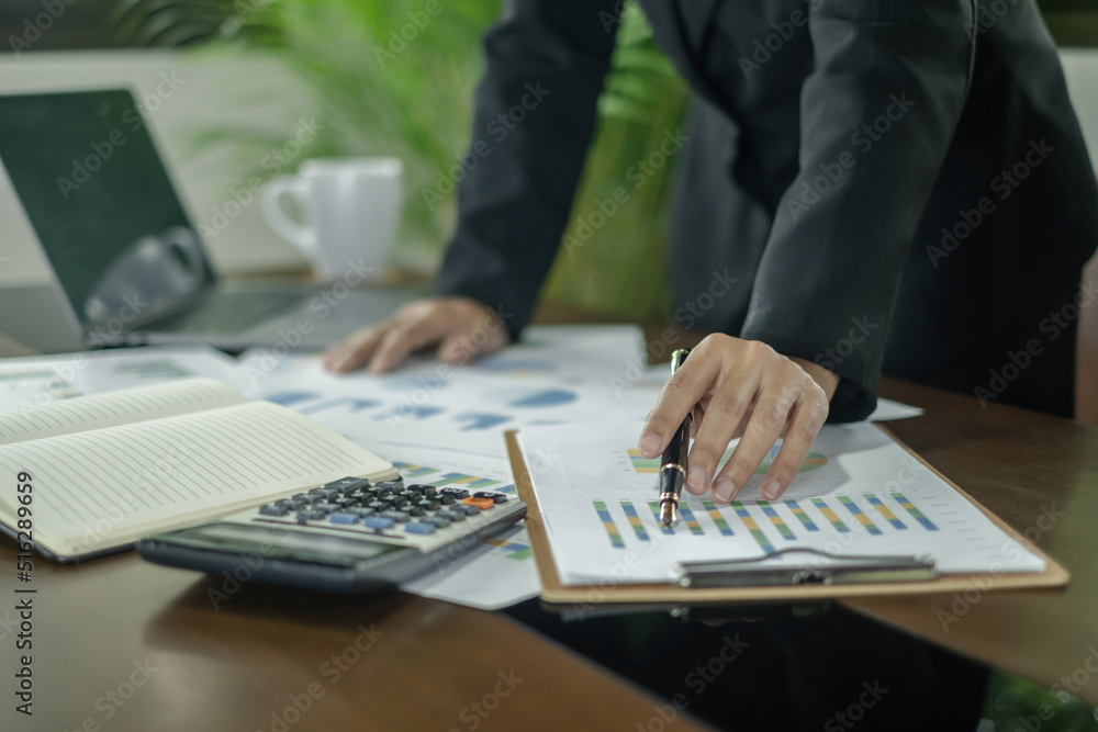 The businesswoman hand sits at their desks and calculates financial graphs showing the results of their investments planning the process of successful business growth The businesswoman hand sits at their desks and calculates financial graphs showing the results of their investments planning the process of successful business growth