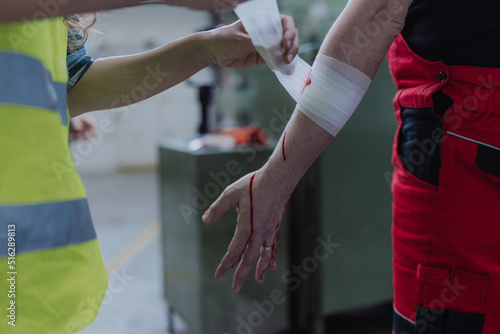 Woman is helping her colleague after accident in factory. First aid support on workplace concept. © Halfpoint