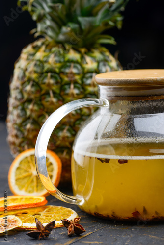 pineapple tea in a teapot on a dark background with lemons 