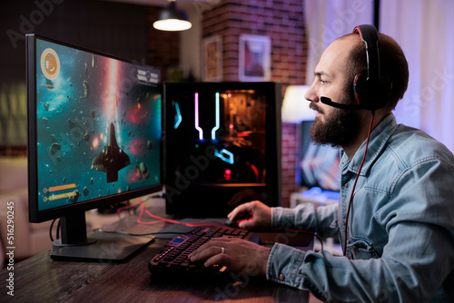 Cheerful person playing action shooting video games competition in living room with neon lights. Male player streaming live rpg gameplay tournament on computer, enjoying shooter play.