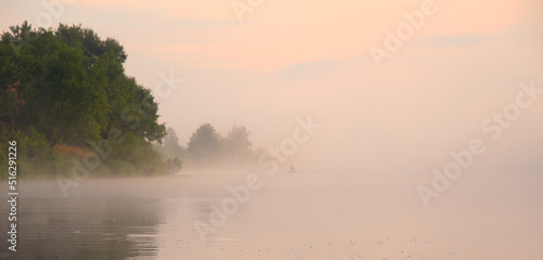 fog over the river at sunset a fisherman in a boat on the water © makam1969