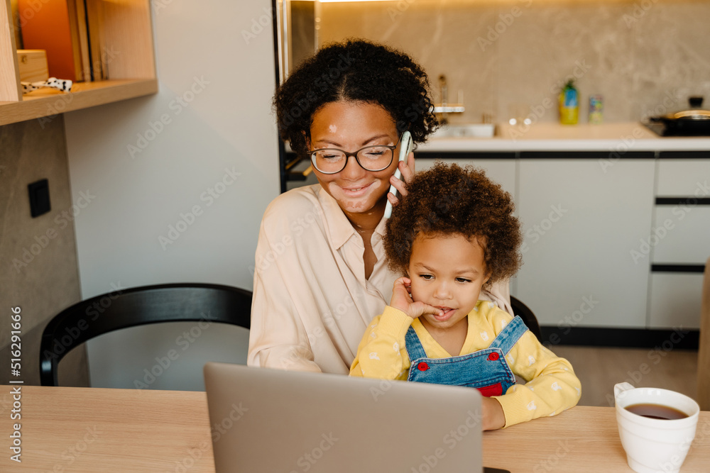 African american woman sitting at table with her son and using laptop African american woman sitting at table with her son and using laptop