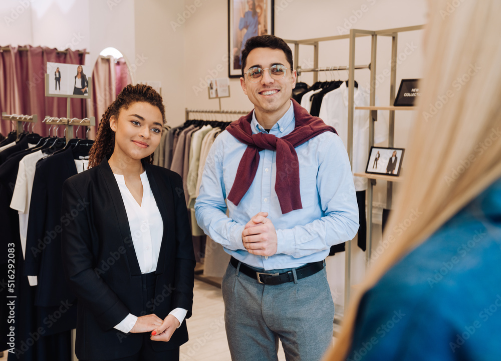 Multiracial man and woman working with customer in clothes store