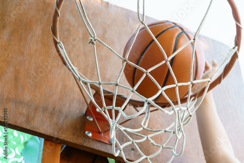 close view of hands throwing a ball into a basketball hoop, teenage boy playing at home in the backyard, outdoor activities on summer vacation