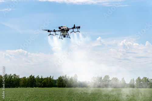 Modern technologies in agriculture. An industrial drone flies over a green field and sprays useful pesticides to increase productivity and destroys harmful insects. increase productivity photo