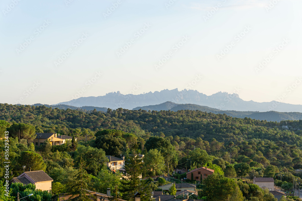 View of the houses in the forest of the town of Talamanca in Bages and the mountains of Montserrat in the background