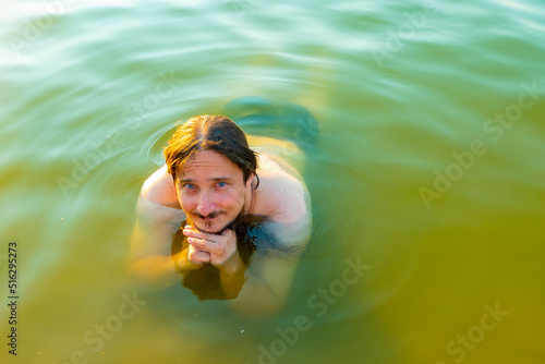  caucasian man floating in a swimming lake with blue water
