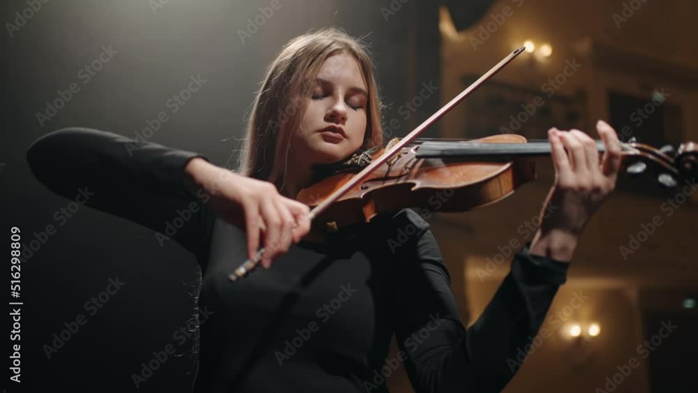 young woman violinist is playing violin in music hall, portrait of woman with fiddle, classic music concert, first violin in orchestra, soloist on scene young woman violinist is playing violin in music hall, portrait of woman with fiddle, classic music concert, first violin in orchestra, soloist on scene