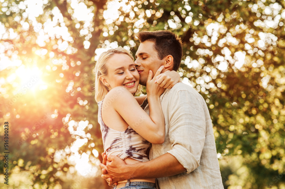 summer holidays, love and people concept - happy young couple kissing and hugging outdoors summer holidays, love and people concept - happy young couple kissing and hugging outdoors
