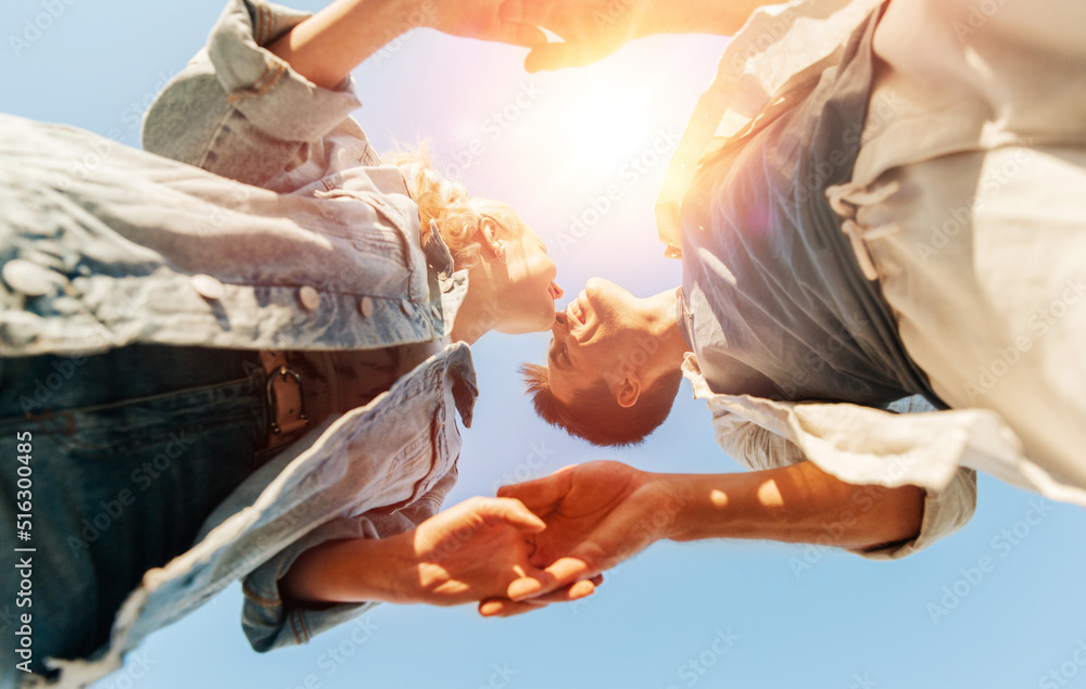 summer holidays, love and people concept - happy young couple holding hands under blue sky, from below