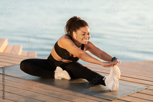 Attractive well-fit black woman exercising outdoors next to water