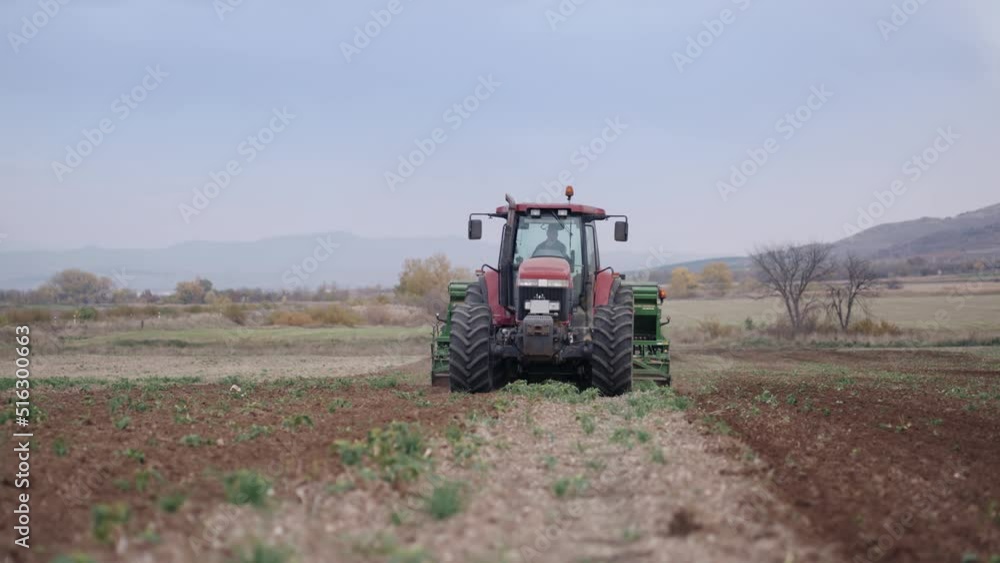 Farmer with tractor seeding crops at field, slow motion Farmer with tractor seeding crops at field, slow motion