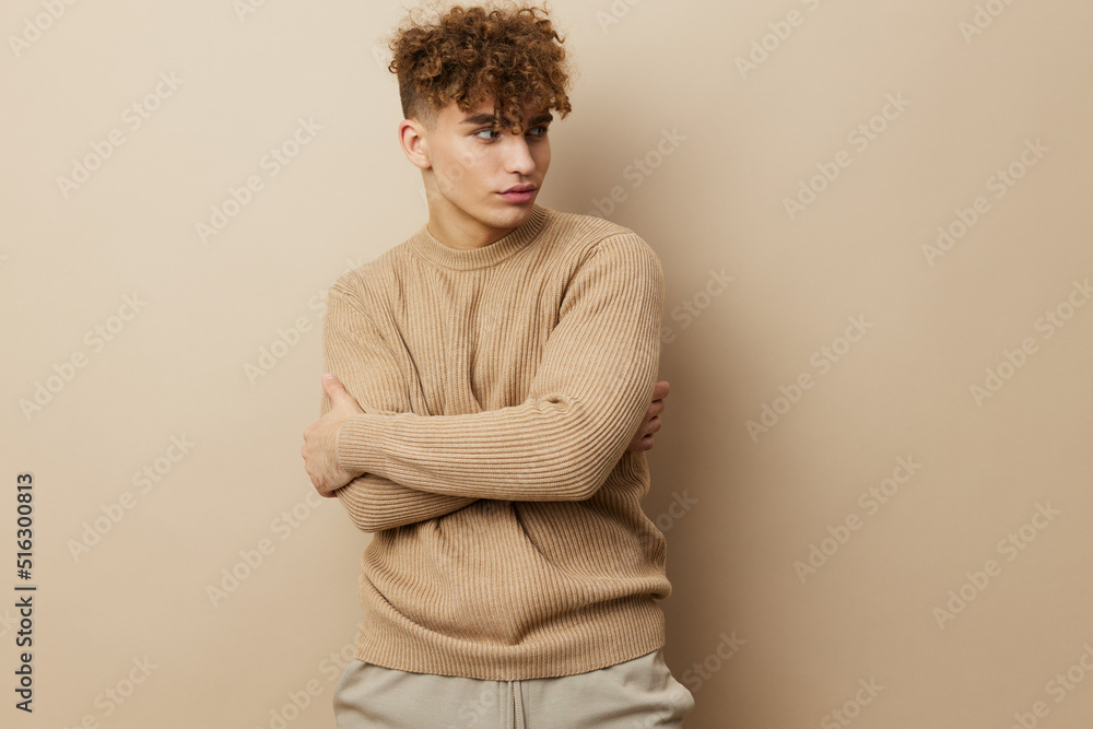 a charming, handsome man stands on a beige background in a sweatshirt and embraces himself with his arms, smiling pleasantly a charming, handsome man stands on a beige background in a sweatshirt and embraces himself with his arms, smiling pleasantly