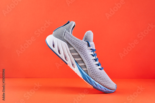 Stability and cushion running shoes. New unbranded running sneaker or trainer on orange background. Men's sport footwear.