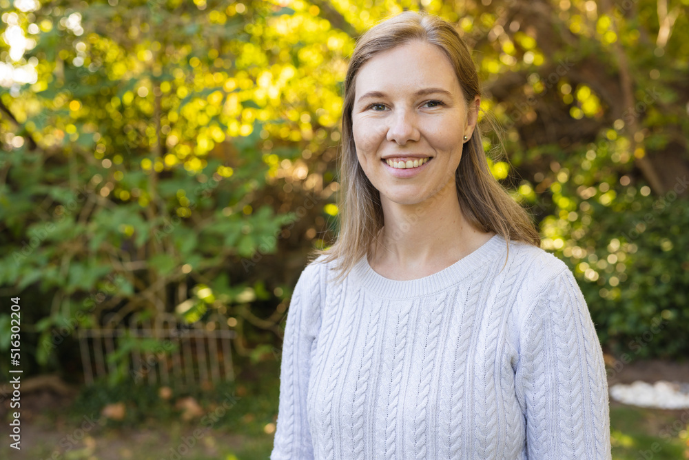 Portrait of smiling beautiful caucasian mid adult lesbian woman standing against lush plants in yard Portrait of smiling beautiful caucasian mid adult lesbian woman standing against lush plants in yard