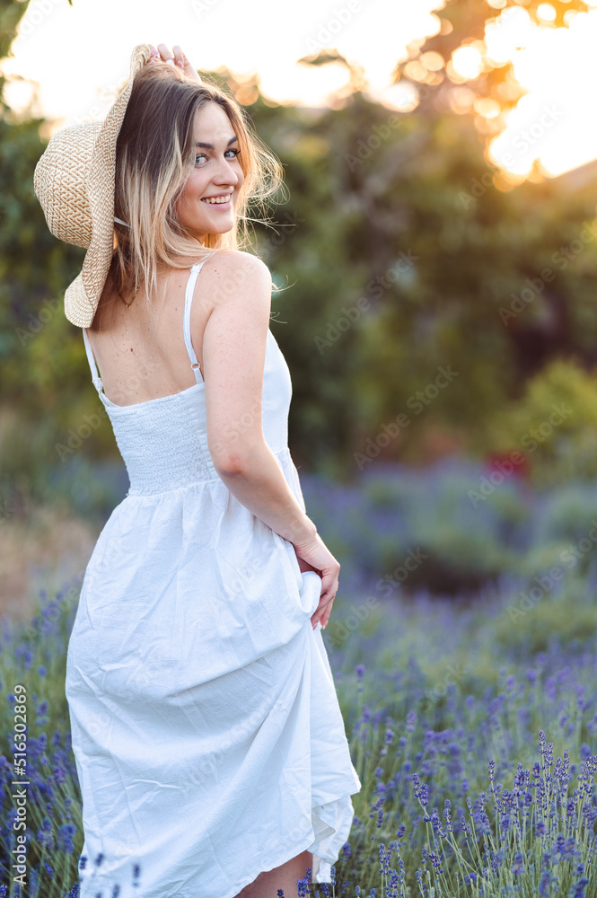 Close-up Portrait of Smiling Girl Standing with her Back, Hand Near her Hat on Lavender Meadow. Close-up Portrait of Smiling Girl Standing with her Back, Hand Near her Hat on Lavender Meadow.