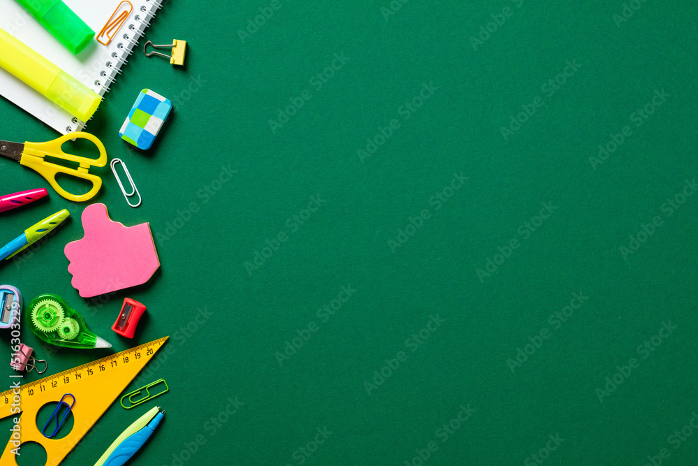 Back to school concept. Flat lay colorful school stationery on green background. Top view. Copy space