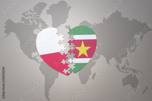puzzle heart with the national flag of suriname and poland on a world map background.Concept.