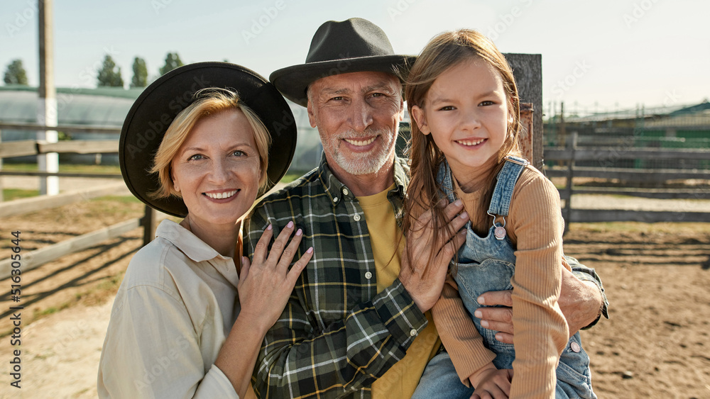 Portrait of grandparents and granddaughter on farm