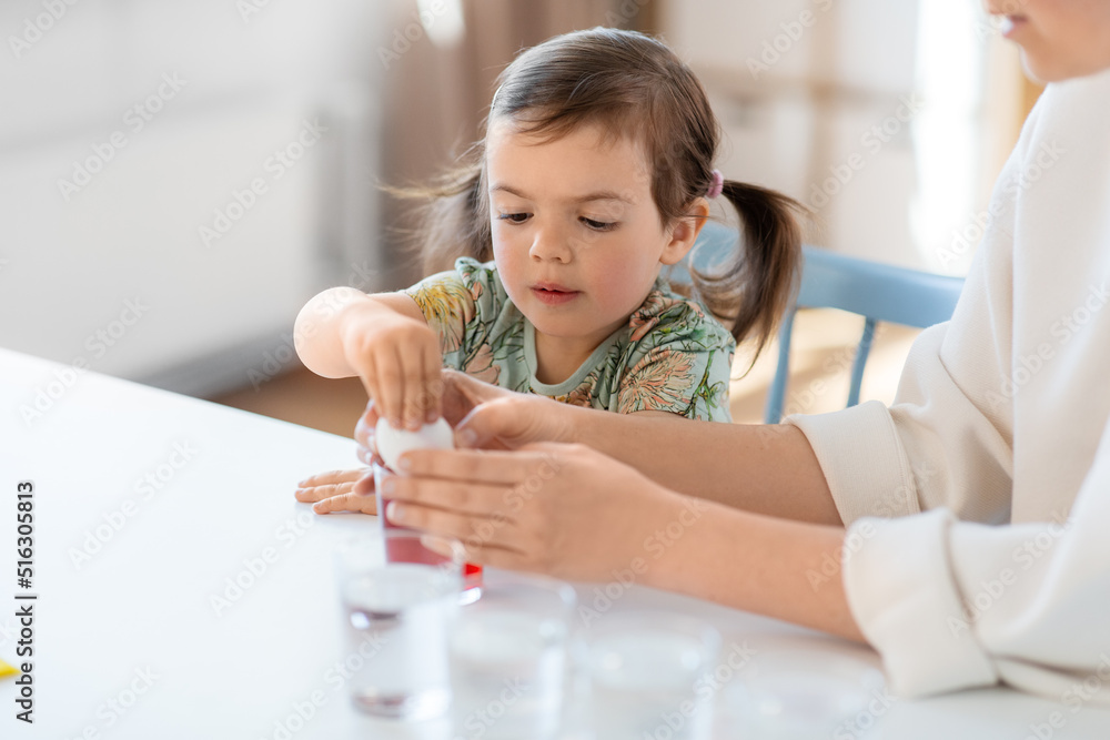 holidays, family and people concept - happy mother and little baby daughter dyeing easter eggs with colors at home holidays, family and people concept - happy mother and little baby daughter dyeing easter eggs with colors at home