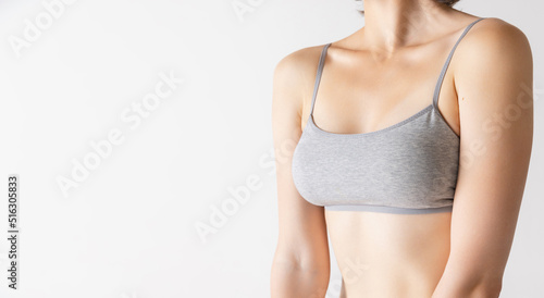 Cropped image of slender female body, breast and shoulders isolated over grey studio background. Concept of beauty, body and skin care, fitness, health