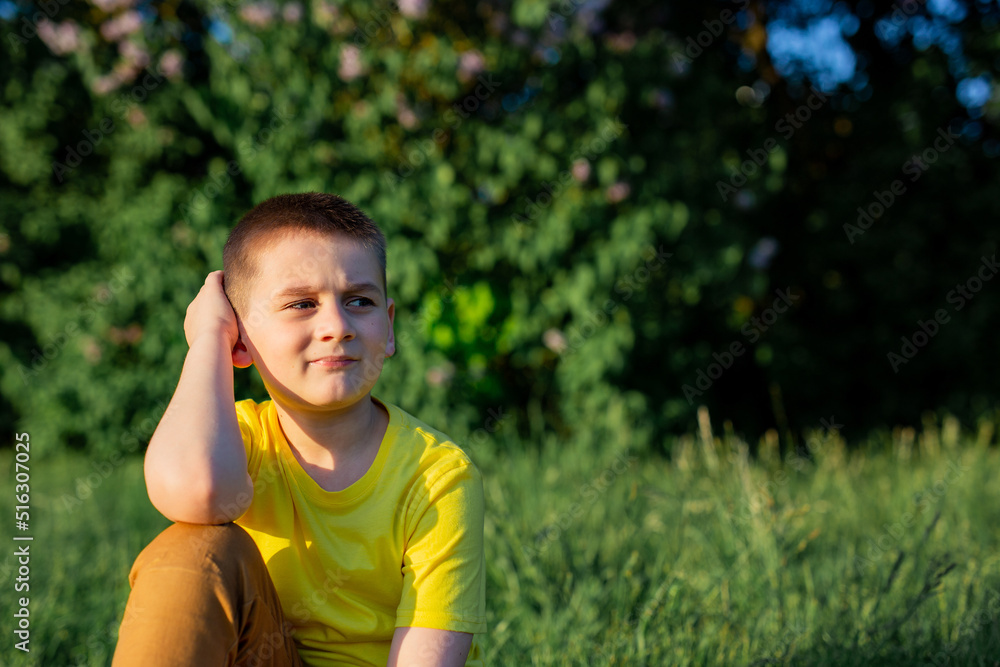 schoolboy boy in a yellow T-shirt sits outdoors schoolboy boy in a yellow T-shirt sits outdoors