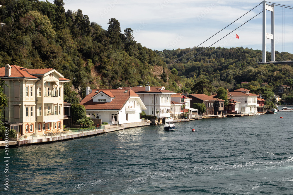 View of a small fishing boat, historical and traditional mansions by Bosphorus in Kanlica area of Asian side of Istanbul. It is a sunny summer day. Beautiful travel scene.