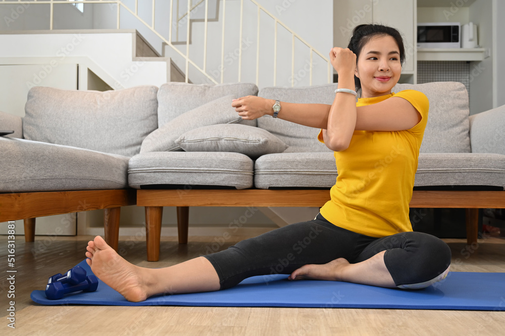 Beautiful woman stretching her arms and exercising in her apartment Beautiful woman stretching her arms and exercising in her apartment