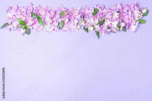 Floral layout of pink and lilac hydrangea flowers on a lilac background. Top view, flat lay. Top border and copy space.