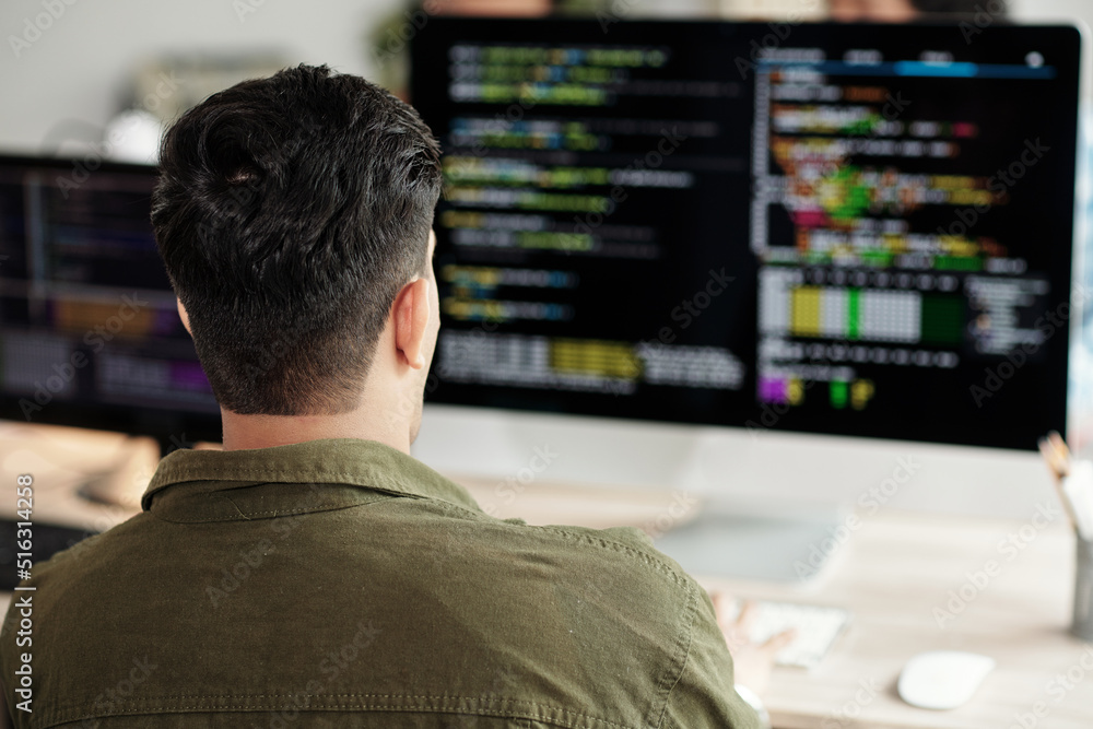 Software developer looking at programming code on computer screen, view ...
