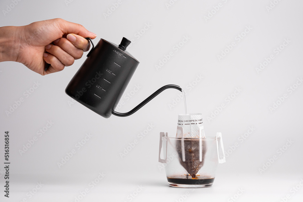 Pouring hot water into into a cup on a black background, Stock image