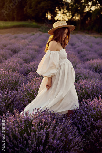 the pregnant girl with a hat in the lavender field on a sunset