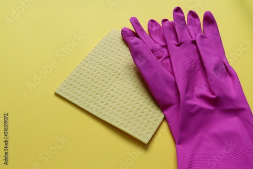 pink rubber gloves and yellow rag on the yellow background © Diana Kozii