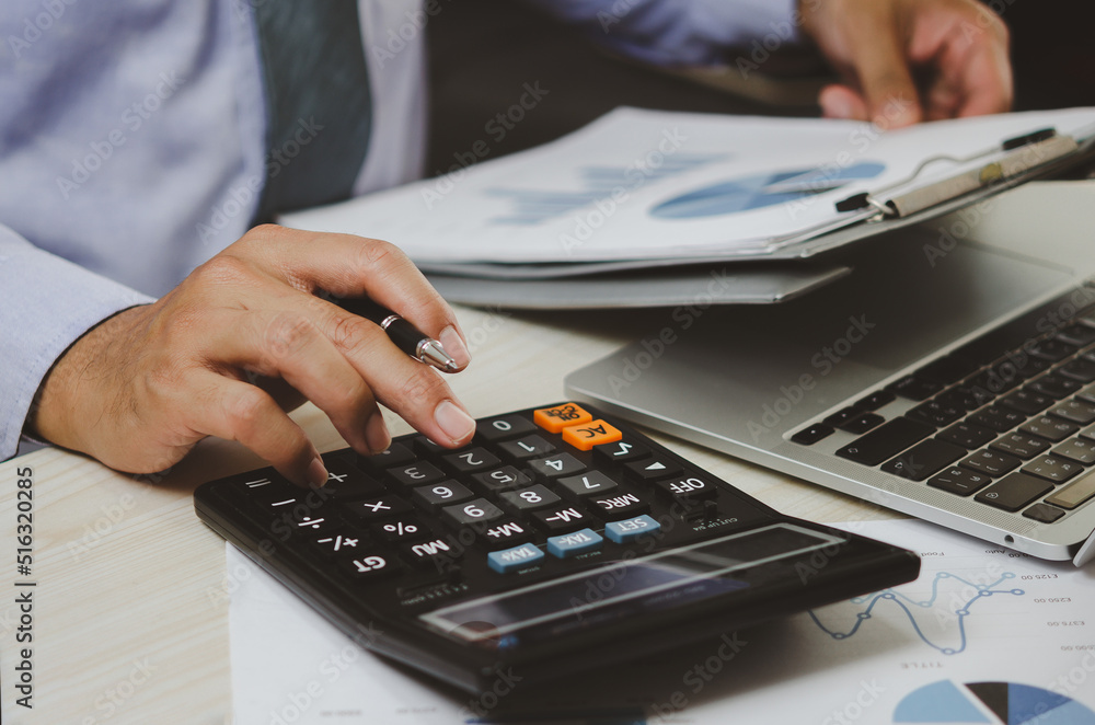 businessman holding calculators and business documents charts statistical data investment analysis and tax accounting. businessman holding calculators and business documents charts statistical data investment analysis and tax accounting.