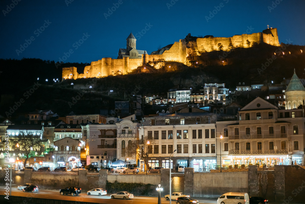 Tbilisi, Georgia Scenic View Of Impregnable Fortress Narikala Fortress. Ancient Fortress Narikala In Old Town Of Tbilisi. Caucasus. Night Traffic. Early Spring Season.