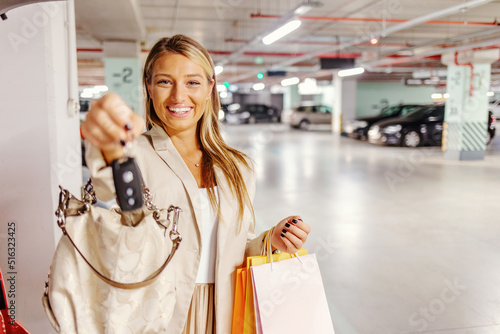 Portrait of a cheerful Caucasian woman holding keys to her new car. Happy young woman showing the keys of her new car.