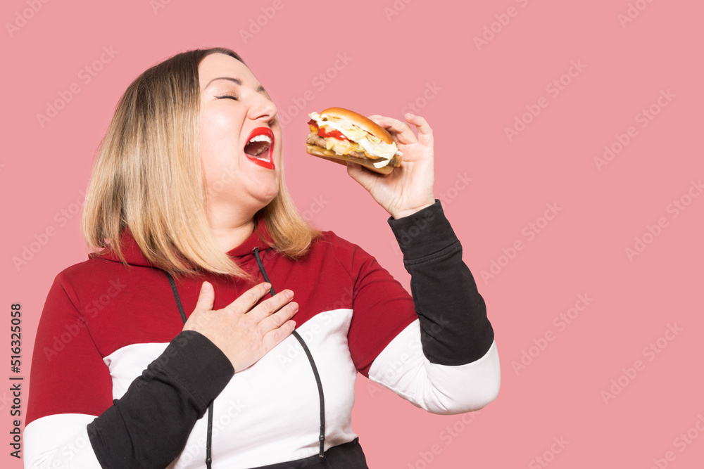 Cheerful woman with appetite looks at a delicious burger. . Unhealthy food. Cheerful woman with appetite looks at a delicious burger. . Unhealthy food.