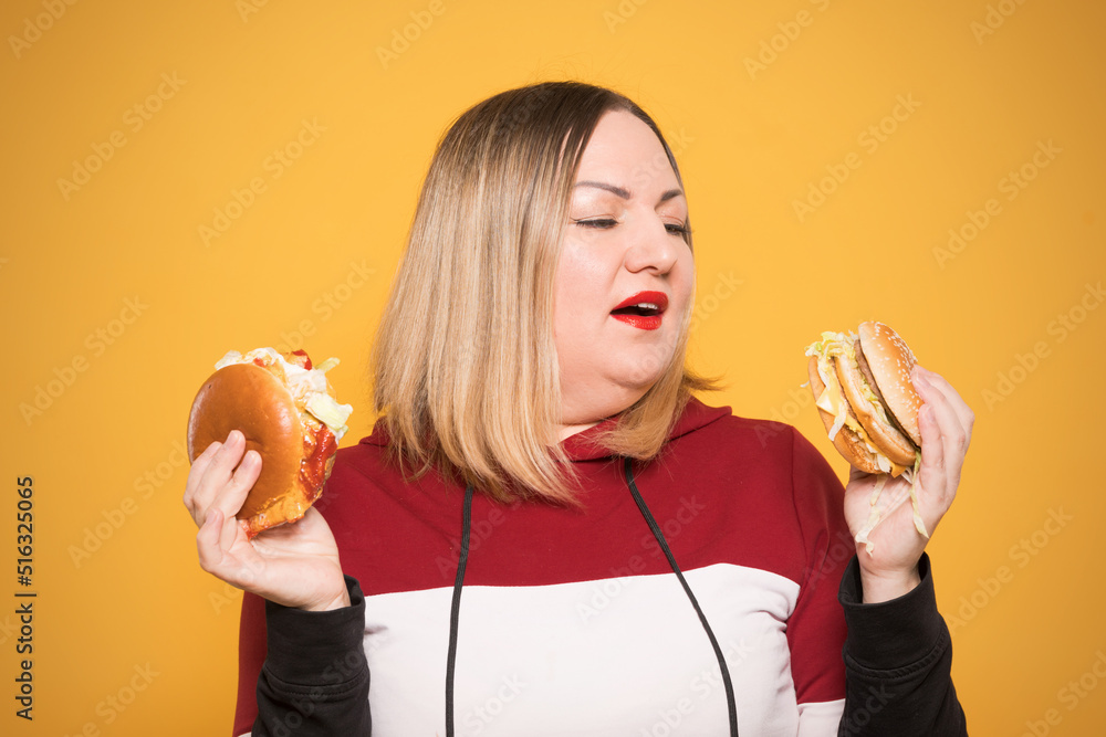 Cheerful woman with appetite looks at a delicious burger. . Unhealthy food.
