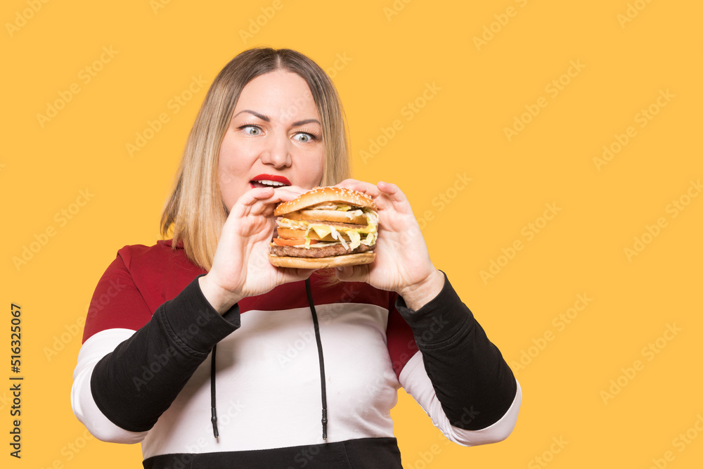 Cheerful woman with appetite looks at a delicious burger. . Unhealthy food. Cheerful woman with appetite looks at a delicious burger. . Unhealthy food.