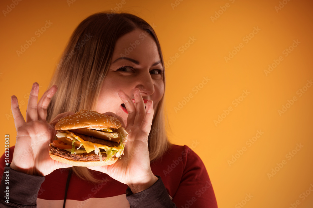 A hungry woman is biting a big tasty burger A hungry woman is biting a big tasty burger
