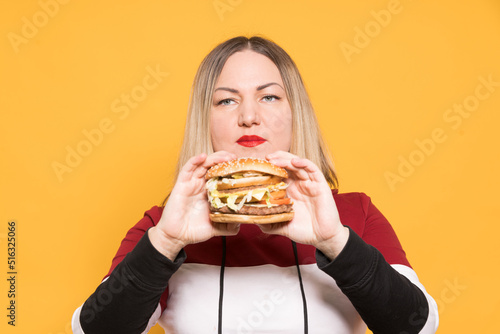 Cheerful woman with appetite looks at a delicious burger. . Binge eating