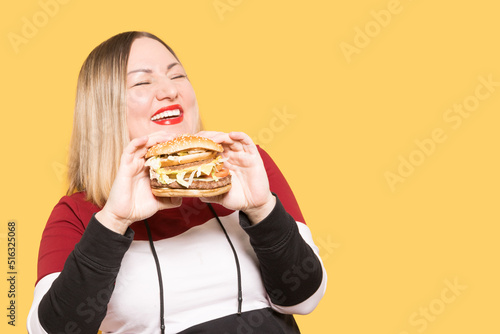 Body positive Cheerful woman with appetite looks at a delicious burger. . Binge eating