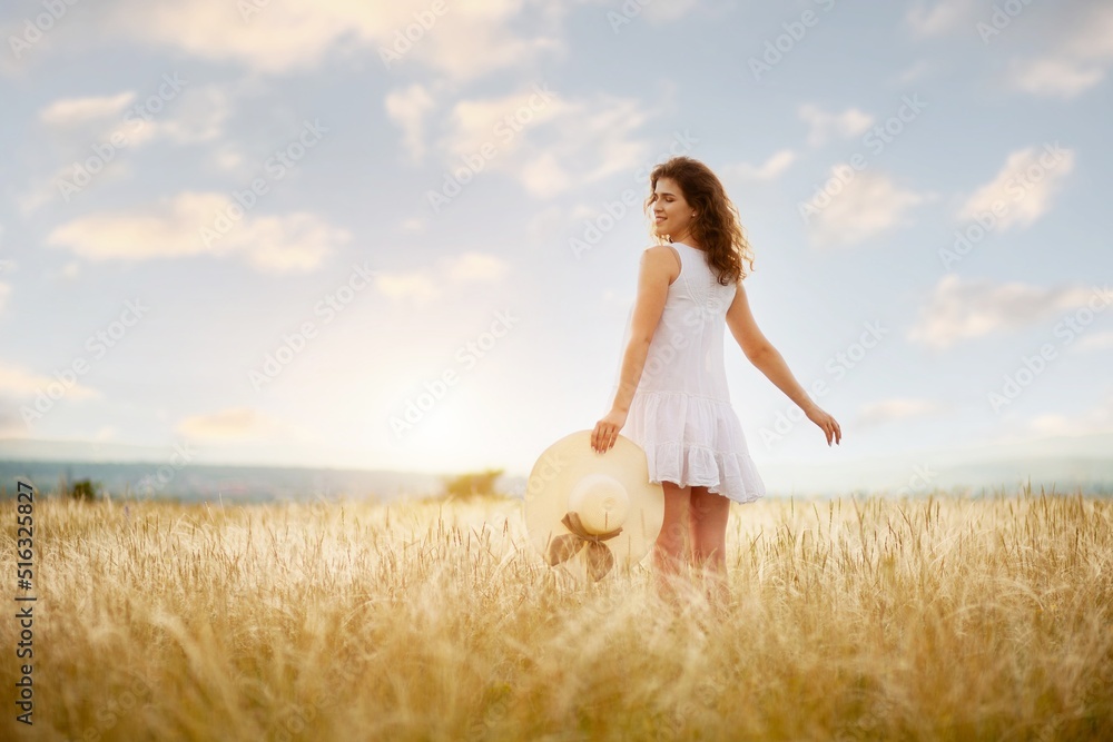 Woman in hat on the field with flowers on the field background Woman in hat on the field with flowers on the field background